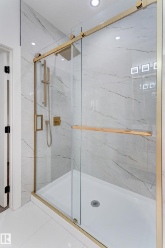 Modern shower enclosure with gold-finish hardware, clear glass sliding door, and a rain showerhead - 4723 17 Avenue Sw, Edmonton, AB - Indoor Photo Showing Bathroom