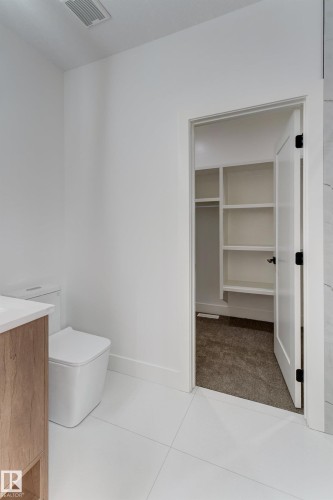 Contemporary bathroom featuring white tile flooring and a built-in wood-finish vanity with a light countertop - 4723 17 Avenue Sw, Edmonton, AB - Indoor Photo Showing Bathroom