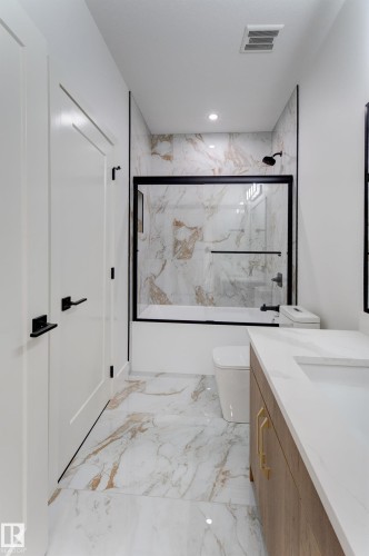 Bathroom featuring a white and gold marbled tile floor, complementary shower surround, a sleek white vanity with a light countertop, gold-toned hardware, and matte black fixtures - 4723 17 Avenue Sw, Edmonton, AB - Indoor Photo Showing Other Room