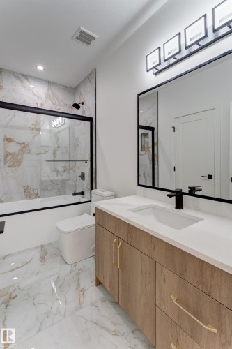 Bathroom featuring a wood-finish vanity with a white countertop and gold-tone hardware - 4723 17 Avenue Sw, Edmonton, AB - Indoor