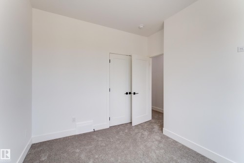 Neutral-toned carpeting paired with white walls, baseboards, and interior doors - 4723 17 Avenue Sw, Edmonton, AB - Indoor Photo Showing Other Room