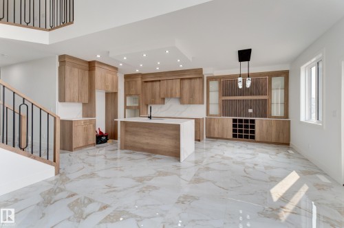 Expansive kitchen featuring a central island with a sink, wood-finish cabinetry, integrated wine storage, white countertops, and recessed lighting - 4723 17 Avenue Sw, Edmonton, AB - Indoor