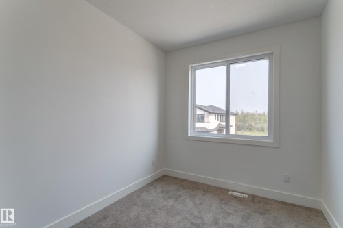 Neutral-toned room featuring a window with white trim, light gray carpeting, white walls, and white baseboards - 4723 17 Avenue Sw, Edmonton, AB - Indoor Photo Showing Other Room