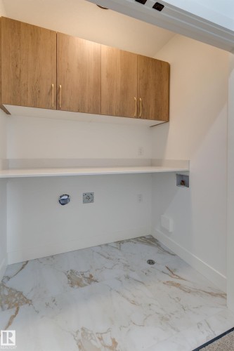 White and gold vein tile flooring complements a white countertop and light wood-finish cabinetry - 4723 17 Avenue Sw, Edmonton, AB - Indoor