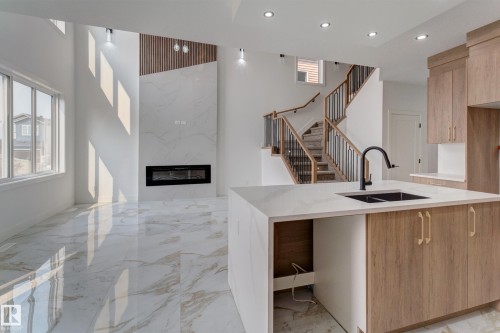 Open concept interior featuring high ceilings, large windows, and large format marble-look tile flooring - 4723 17 Avenue Sw, Edmonton, AB - Indoor Photo Showing Kitchen With Double Sink