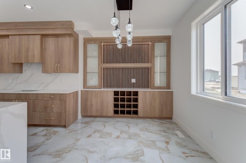 Light wood-finish cabinetry with gold-tone hardware, white and grey marbled flooring, and a built-in wine rack - 4723 17 Avenue Sw, Edmonton, AB - Indoor Photo Showing Other Room