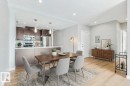 Open-concept living space featuring wood-finish flooring, a kitchen with dark wood cabinetry, stainless steel appliances, and a breakfast bar with pendant lighting - #910 10238 103 St Nw, Edmonton, AB  - Indoor Photo Showing Dining Room 