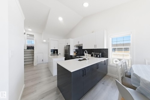 Kitchen featuring a vaulted ceiling with recessed lighting, light wood-finish flooring, and a two-tone island with a light-colored countertop - 3799 21 Street Nw, Edmonton, AB - Indoor Photo Showing Other Room