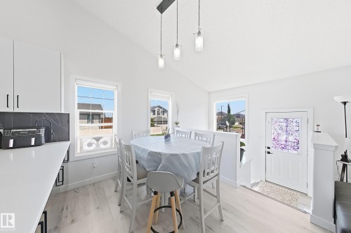 Vaulted ceiling over a dining area with pendant lighting and wood-finish flooring - 3799 21 Street Nw, Edmonton, AB - Indoor