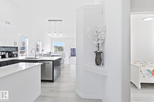Contemporary kitchen featuring white cabinetry, dark lower cabinets, and light countertops - 3799 21 Street Nw, Edmonton, AB - Indoor Photo Showing Kitchen With Upgraded Kitchen