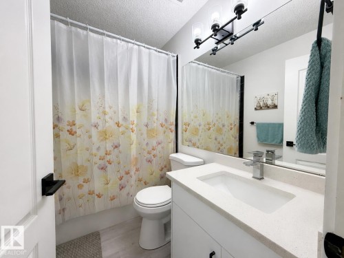White vanity with an integrated sink and chrome faucet - 3799 21 Street Nw, Edmonton, AB - Indoor Photo Showing Bathroom