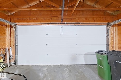 White sectional garage door with exposed wood framing and a concrete floor - 3799 21 Street Nw, Edmonton, AB - Indoor Photo Showing Garage