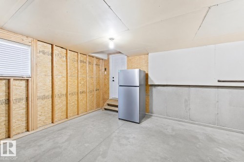 Unfinished basement space featuring exposed wood framing, concrete foundation walls, and a window with blinds - 3799 21 Street Nw, Edmonton, AB - Indoor