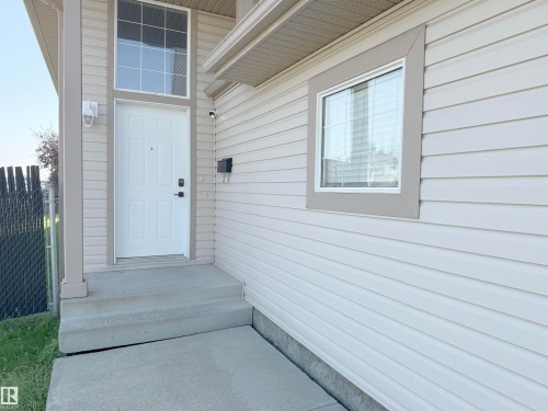 Front entry with a white paneled door, transom window, and concrete steps - 3799 21 Street Nw, Edmonton, AB - Outdoor With Exterior
