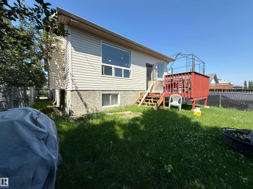 Rear exterior featuring a raised wood deck with red railings, large upper-level windows, and a lower-level window - 3799 21 Street Nw, Edmonton, AB - Outdoor