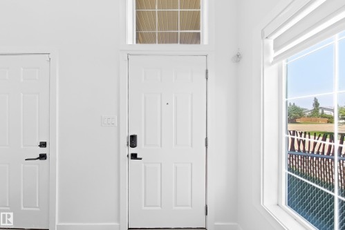 Entryway featuring a panel door with smart lock, transom window, and adjacent window with horizontal blinds - 3799 21 Street Nw, Edmonton, AB - Indoor Photo Showing Other Room