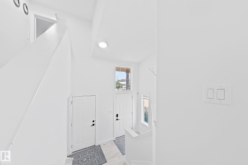 Bright entryway with a prominent staircase featuring white walls and a light wood-finish floor - 3799 21 Street Nw, Edmonton, AB - Indoor Photo Showing Other Room