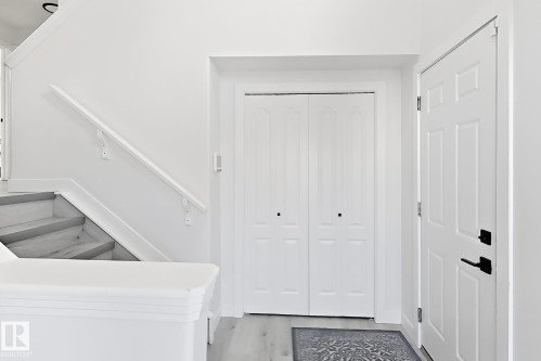 Entryway featuring light-toned flooring, white walls, and a white paneled door with matte black hardware - 3799 21 Street Nw, Edmonton, AB - Indoor