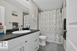 Bathroom featuring a white vanity with dark countertop, undermount sink, and chrome faucet - 