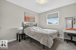 Carpeted interior space featuring a window with cellular blinds, a ceiling-mounted light fixture, and light-toned walls - 