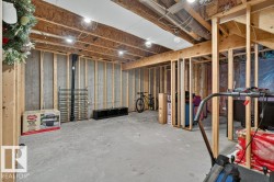 Unfinished basement space featuring exposed wood framing, concrete foundation walls, and a concrete floor - 