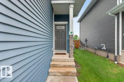 Exterior entry featuring a gray paneled door with upper lites, framed by a brick and column porch support - 