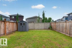 Spacious backyard featuring a storage shed, established lawn, and full privacy fencing - 