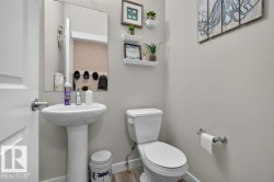 Pedestal sink with a rectangular wall mirror, light gray wall paint, and wood-finish flooring - 