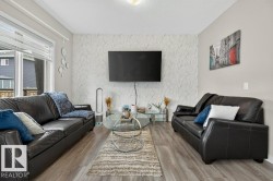Living area featuring wood-finish flooring, a patterned accent wall, and large windows - 