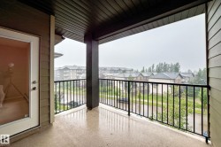 Covered exterior balcony with a concrete surface, black metal railings, and a panel-style ceiling - 