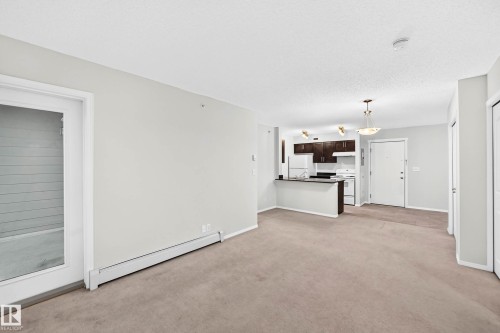 Open-concept living space with light-toned carpeting and a neutral wall palette - #404 12025 22 Av Sw, Edmonton, AB - Indoor