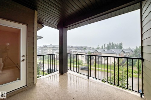 Covered exterior balcony with a concrete surface, black metal railings, and a panel-style ceiling - #404 12025 22 Av Sw, Edmonton, AB - Outdoor With Balcony With Exterior