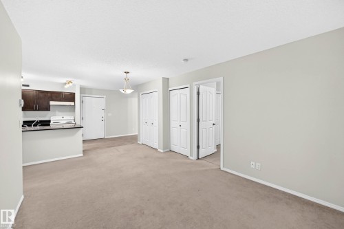 Open-concept living space featuring neutral-toned carpeting and light gray wall paint - #404 12025 22 Av Sw, Edmonton, AB - Indoor Photo Showing Kitchen