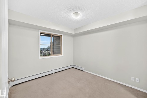 Neutral-toned room featuring a single window with a light-colored frame, light gray walls, and light brown carpeting - #404 12025 22 Av Sw, Edmonton, AB - Indoor Photo Showing Other Room