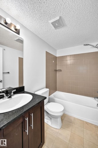 Full bathroom featuring a dark wood-finish vanity with a dark countertop, white oval sink, and chrome faucet - #404 12025 22 Av Sw, Edmonton, AB - Indoor Photo Showing Bathroom