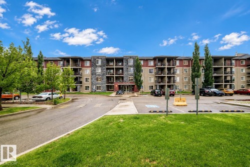 Multi-story residential building featuring balconies, stone façade elements, and mature trees - #404 12025 22 Av Sw, Edmonton, AB - Outdoor With Balcony With Facade