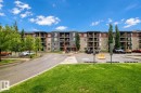 Multi-story residential building featuring balconies, stone façade elements, and mature trees - #404 12025 22 Av Sw, Edmonton, AB  - Indoor Photo Showing Kitchen With Double Sink 