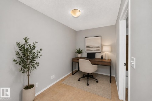 Neutral wall finish, ceiling-mounted light fixture, tile flooring, built-in desk with drawers - #404 12025 22 Av Sw, Edmonton, AB - Indoor Photo Showing Other Room