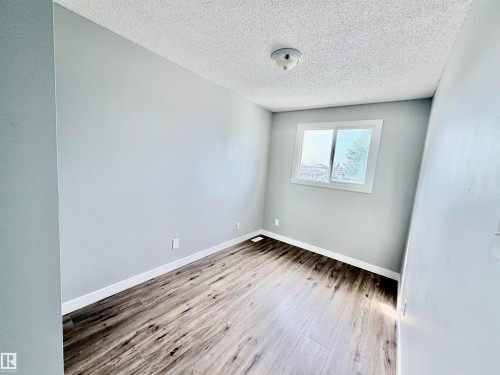 Bright room featuring wood-finish flooring, light gray walls, white trim, and a window for natural illumination - 11430 139 Avenue Nw, Edmonton, AB - Indoor Photo Showing Other Room