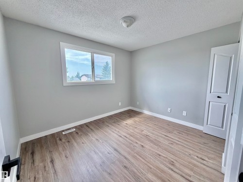 Spacious room featuring wood-finish flooring, light grey walls, white trim, and a double window - 11430 139 Avenue Nw, Edmonton, AB - Indoor Photo Showing Other Room