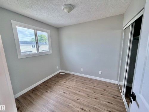 Neutral gray walls with white trim, wood-finish flooring, and a window providing natural light - 11430 139 Avenue Nw, Edmonton, AB - Indoor Photo Showing Other Room