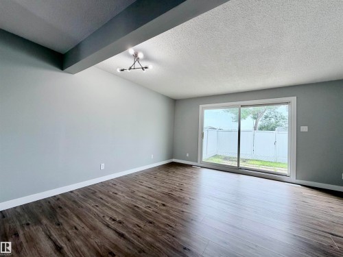 Spacious room featuring wood-finish flooring, light grey walls, and white baseboards - 11430 139 Avenue Nw, Edmonton, AB - Indoor Photo Showing Other Room