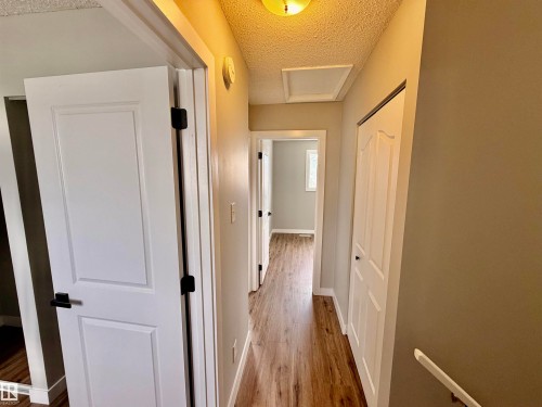 Hallway featuring wood-finish flooring, white paneled doors with matte black hardware, and an overhead light fixture - 11430 139 Avenue Nw, Edmonton, AB - Indoor Photo Showing Other Room