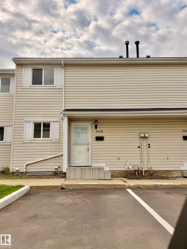 Entry-level townhome featuring light-colored vinyl siding, white trim, and a concrete stoop - 11430 139 Avenue Nw, Edmonton, AB - Outdoor