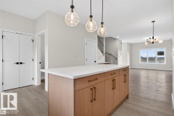 Kitchen island featuring a white countertop, wood-finish cabinetry, and bronze hardware - 