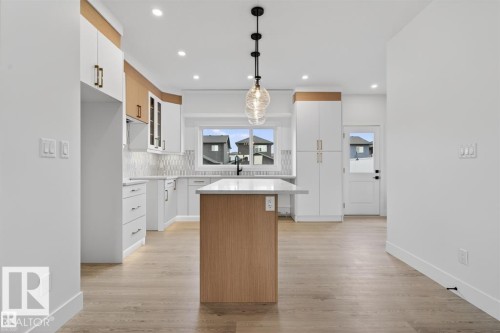 Modern kitchen featuring wood-finish flooring, a central island with a quartz countertop, and a contemporary pendant light fixture - 43 River Birch Way, St. Albert, AB - Indoor Photo Showing Kitchen With Upgraded Kitchen