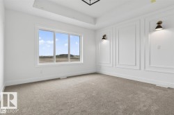 Spacious room featuring a tray ceiling and bright, neutral carpeting - 