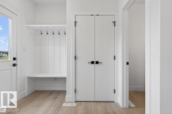 Entryway featuring a built-in bench with storage, overhead shelf, and matte black coat hooks - 