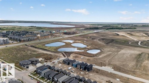 Aerial depiction of a developing neighborhood featuring multiple residential structures, bodies of water, and surrounding open land - 43 River Birch Way, St. Albert, AB - Outdoor With View