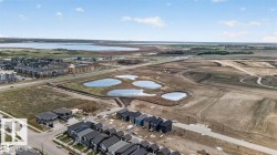Aerial depiction of a developing neighborhood featuring multiple residential structures, bodies of water, and surrounding open land - 